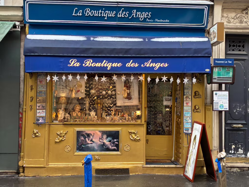 La devanture de La Boutique des Anges, rue Yvonne Le Tac : un store bleu et une façade dorée ornée de chérubins.