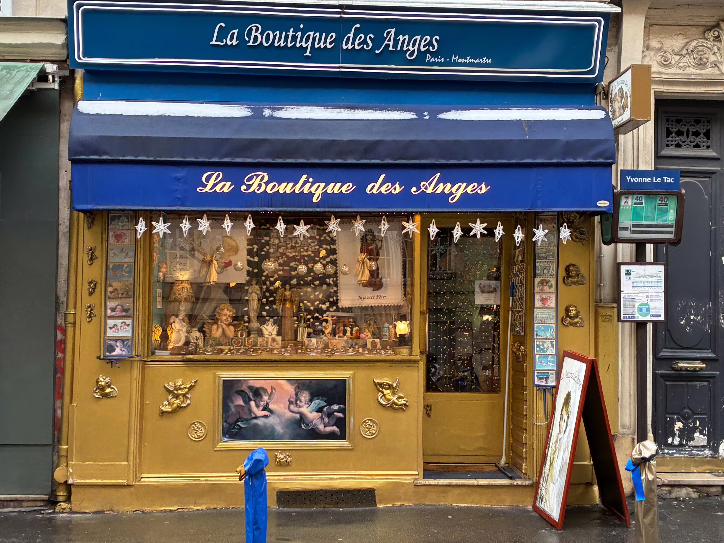 La devanture de La Boutique des Anges, rue Yvonne Le Tac : un store bleu et une façade dorée ornée de chérubins.