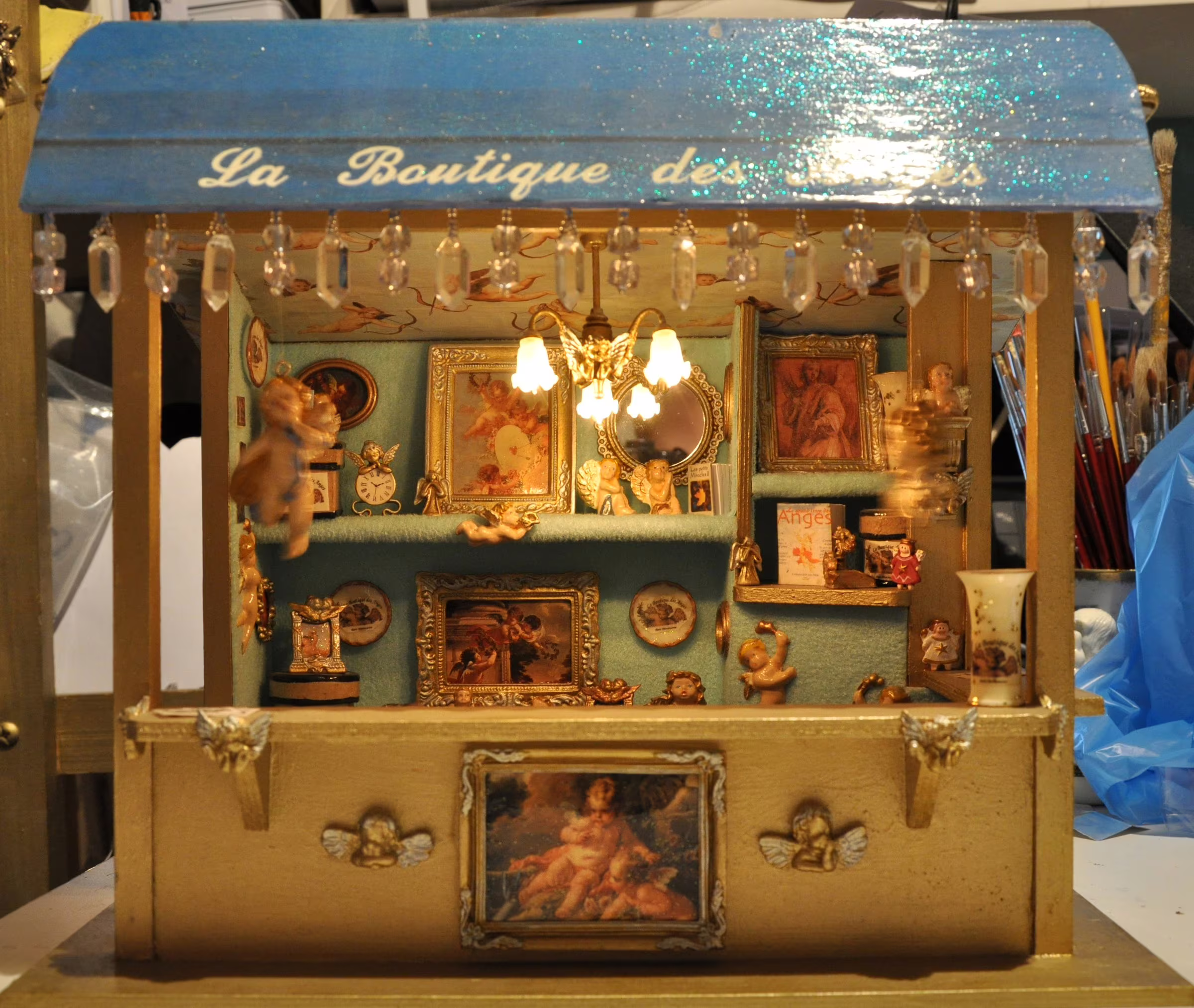 Une miniature du Magasin à l'échelle 1/12, avec ses anges et son mobilier en modèle réduit.